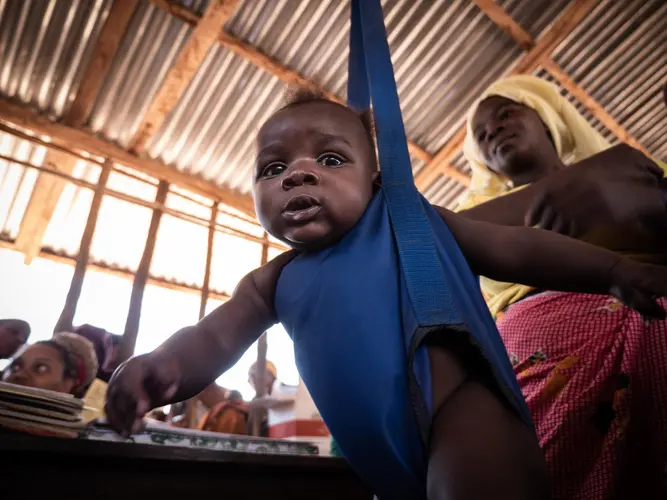 On 27 September, 2019, a boy is weighed, as his mother looks on, during a checkup at a community outreach medical clinic in a village near Mecufi, northern Mozambique.