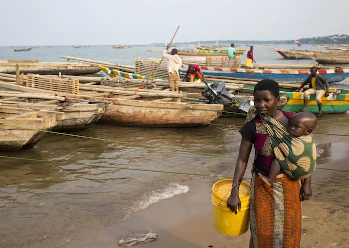 On September 21, 2019, a woman carries a child while collecting water from Lake Tanganyika at the commercial port in Rumonge, Burundi. UNICEF installed handwashing stations at the port to fight the spread of disease.