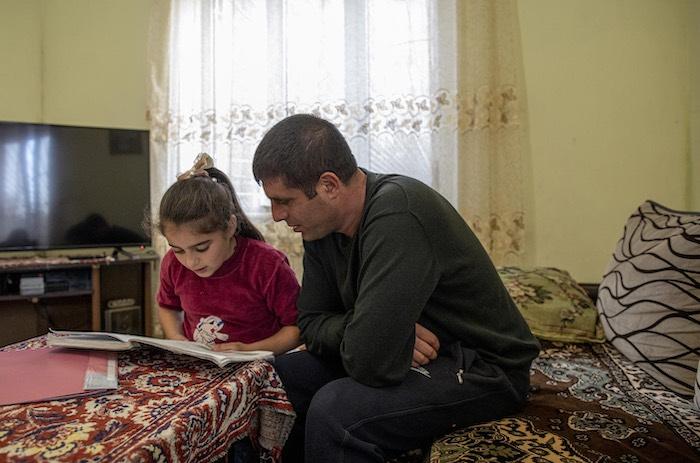 Hripsime Melqonyan, 9, (left) does homework with her father Vladimir Melqonyan, 38, at the family's home in Gyumri, Armenia,