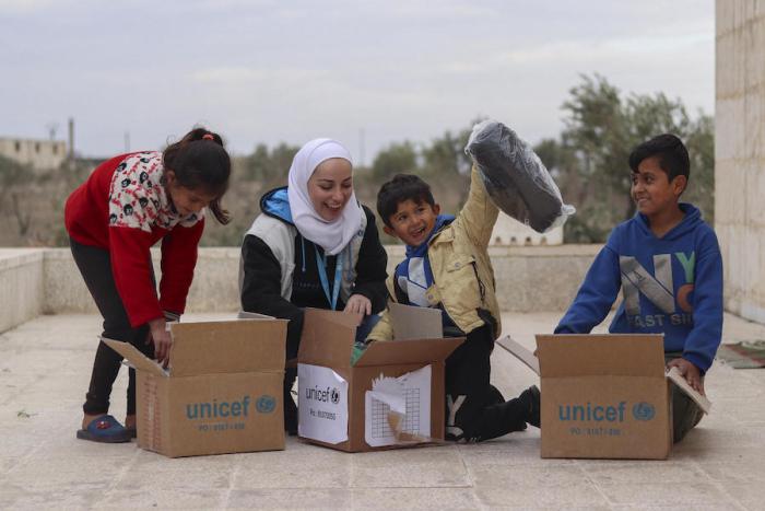 A family in Syria unpacks a box of warm winter clothing provided by UNICEF as part of a previous winter relief program.