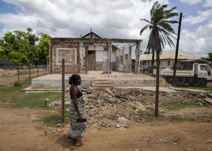 On March 5, 2020, a woman walks past part of the hospital destroyed by a cyclone in Buzi, Mozambique in 2019.