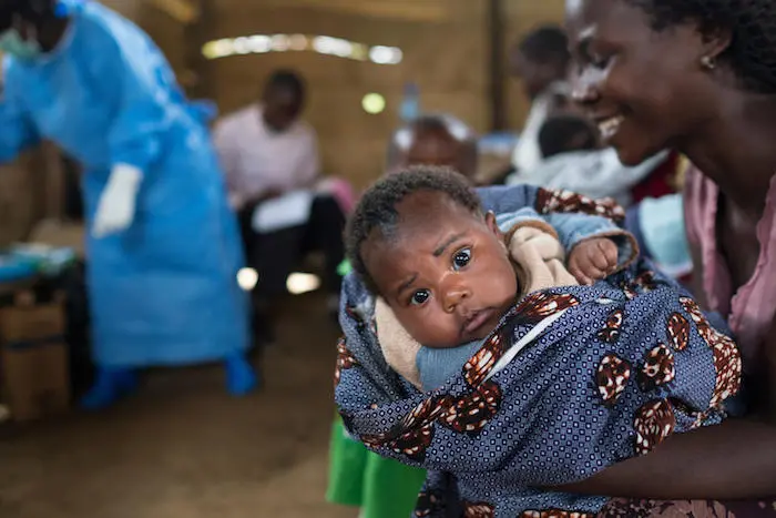 A mother prepares her baby to receive lifesaving vaccines at a UNICEF-supported clinic in the village of Kuka, North Kivu province, DR Congo. A mother prepares her baby to receive lifesaving vaccines at a UNICEF-supported clinic in the village of Kuka, North Kivu province, DR Congo.