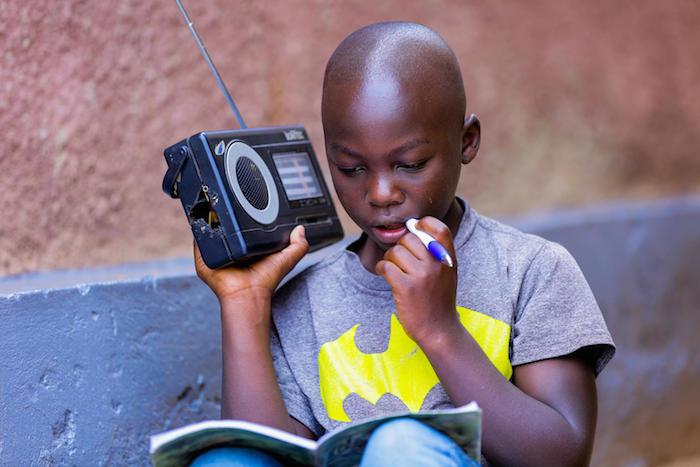 An 11-year-old boy in Rwanda whose school has closed in response to COVID-19 listens to his lessons on the radio.