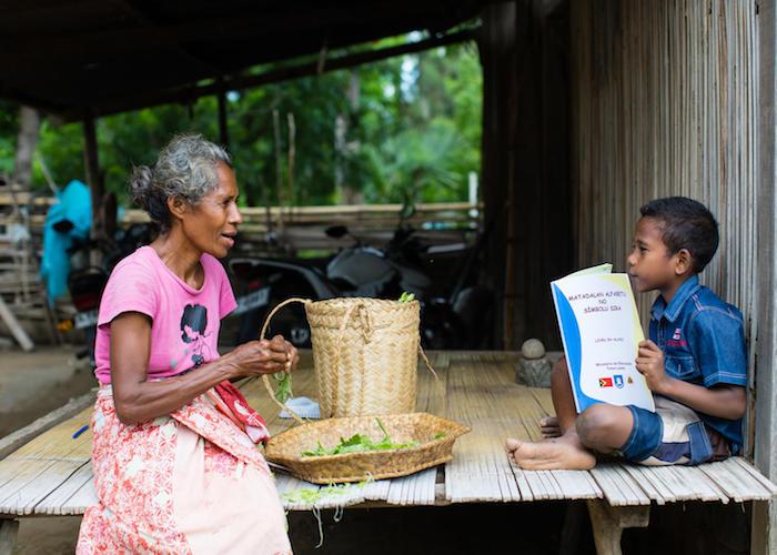 On 14 April 2020, a boy reads as his grandmother looks on in Timor-Leste. The book is part of a series of audio-visual and printed material produced by the Ministry of Education and UNICEF to help children continue learning during the COVID-19 outbreak.