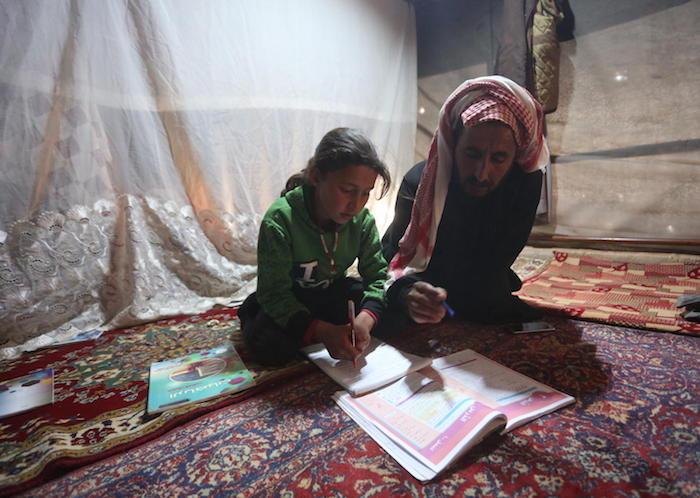 On April 9, 2020, 9-year-old Maria follows a pre-recorded lesson on her father's smartphone in a tent at the Kili IDP camp in rural Idlib, Syria. 
