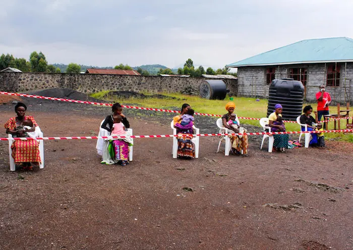 On April 21, 2020, mothers spaced to prevent the spread of COVID-19 wait to have their children vaccinated against measles in Goma, Democratic Republic of the Congo. 