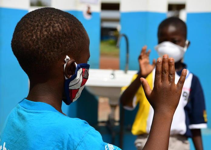 In April 2020, 10-year-old Kolo, left, and his friend Chris, 6, wear masks and wash their hands to prevent the spread of COVID-19 in Korhogo, in the North of Côte d'Ivoire.