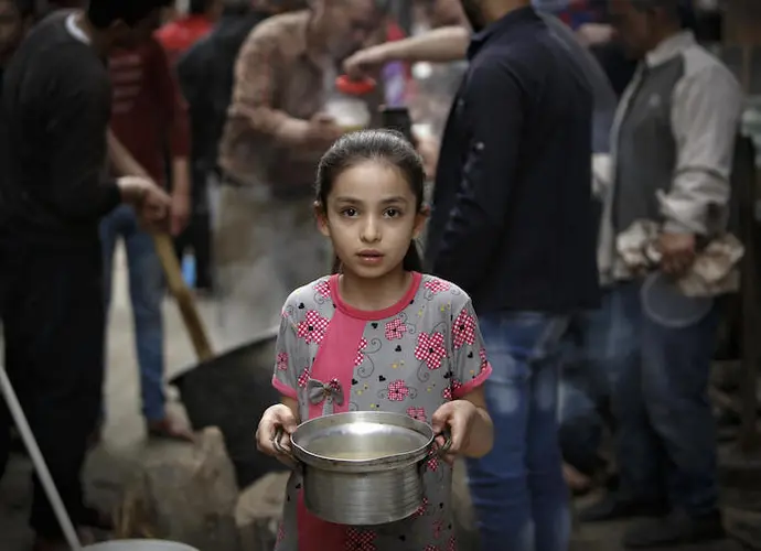 On April 24, 2020 in Gaza City, a Palestinian girl carries a portion of soup, given out to families in need during the Islamic holy month of Ramadan, amid the coronavirus COVID-19 pandemic.