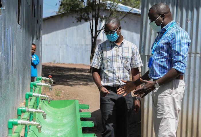 The WASH Chief for UNICEF Ethiopia inspects a hands-free hand washing station designed by a UNICEF WASH engineer. 