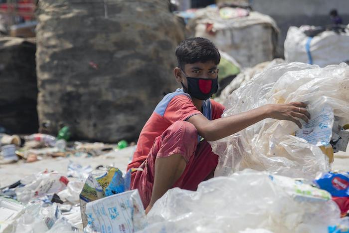 Miajul, 12, sorts through plastic waste at a dump in Shyamol Palli, Dhaka, Bangladesh, looking for material he can sell to recyclers. 
