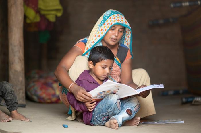 UNICEF supported programs follow up with migrants who have returned to their villages in India. Manguben Patel and her son Vanraj review pre-primary education activity kits for kids during Covid lockdown.
