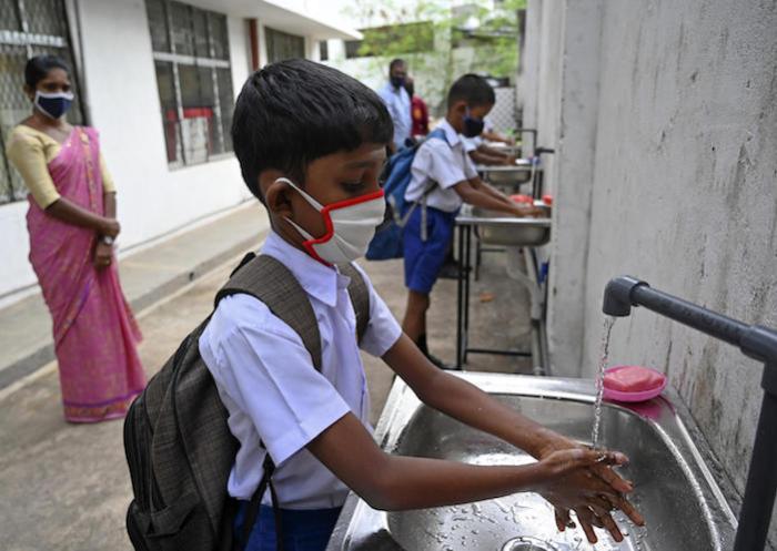 Students wearing facemasks wash their hands inside their school after it was reopened in Colombo, Sri Lanka on 6 July 2020.
