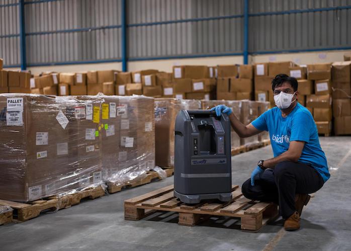 A UNICEF worker examines a shipment of oxygen concentrators at a warehouse in Delhi, India. 