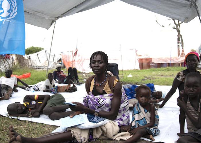 Nyachimach and her eight children have been displaced four times by conflict and flooding in South Sudan, Here, they wait outside a UNICEF-suported health facility in Pibor. 