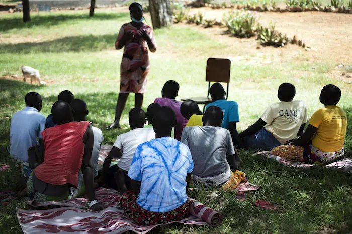 Adolescent girls sit in a cirle in front of an instructor in a park in Uganda Adolescent girls sit in a cirle in front of an instructor in a park in Uganda