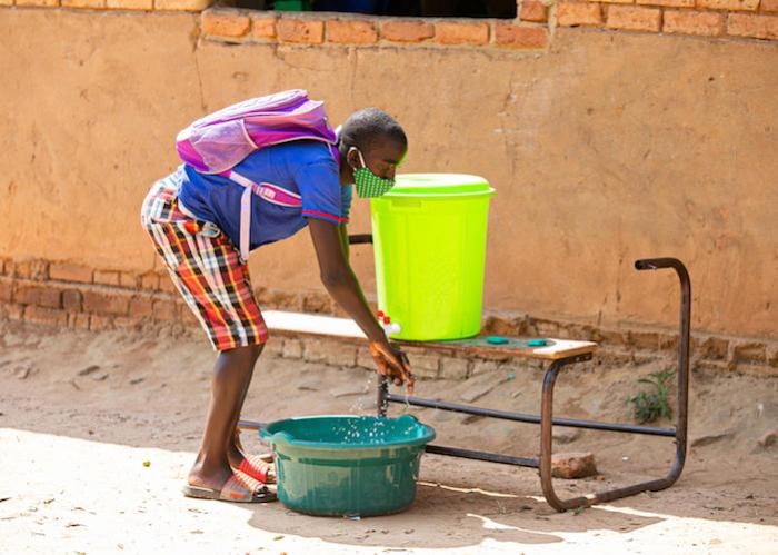 Lovewell, 17, washes hands after attending classes at UNICEF-supported Luwambaza primary school in Malawi in 2020.