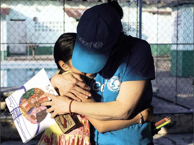 Alejandra, 10, is held by a UNICEF-supported volunteer at the St. Augustine hotel for refugees in Mexico.