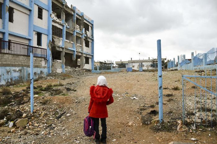 Aya, 14, looks at her old school, damaged by the conflict, in Dara’a Albalad, south Syria, on Feb. 7, 2022.