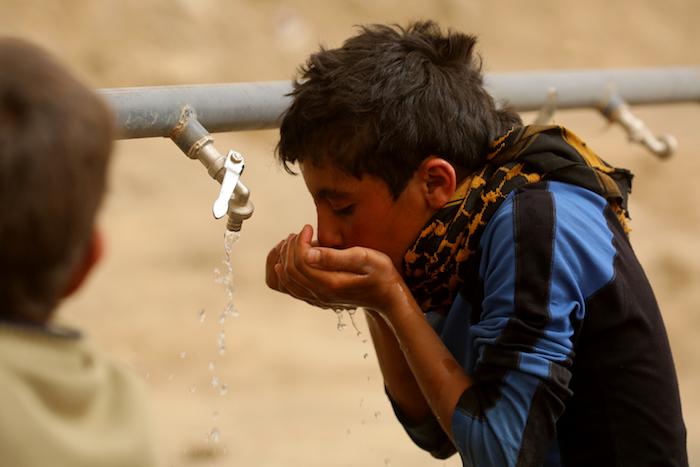 Syrian refugee Mohammad, 13, drinks from a tap installed by UNICEF in Karama camp, rural Ar-Raqqa, Syria.