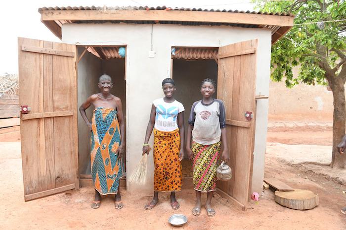 Two young girls with their grandmother in front of their new latrine in the village of Dibobly, Côte d'Ivoire. 