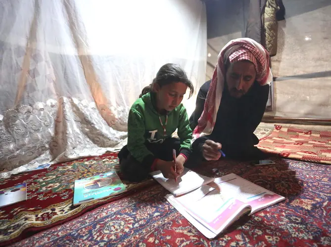 On 9 April 2020, 9-year-old Maria follows a pre-recorded lesson on her father&rsquo;s smartphone in a tent at the Kili IDP camp in rural Idlib.