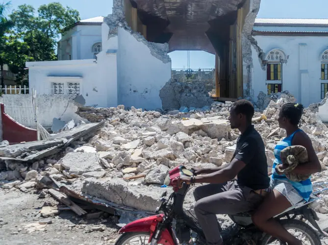 People drive past the remains of the Sacr&eacute; Coeur des Cayes church in Les Cayes on August 15, 2021, after a 7.2-magnitude earthquake struck Haiti&rsquo;s southwest peninsula.