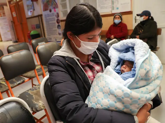 In the city of El Alto, Bolivia, Julia Condori cradles her son, Aaron, as they wait their turn in the UNICEF-supported Mercedes Health Center for the child&rsquo;s latest round of vaccinations.