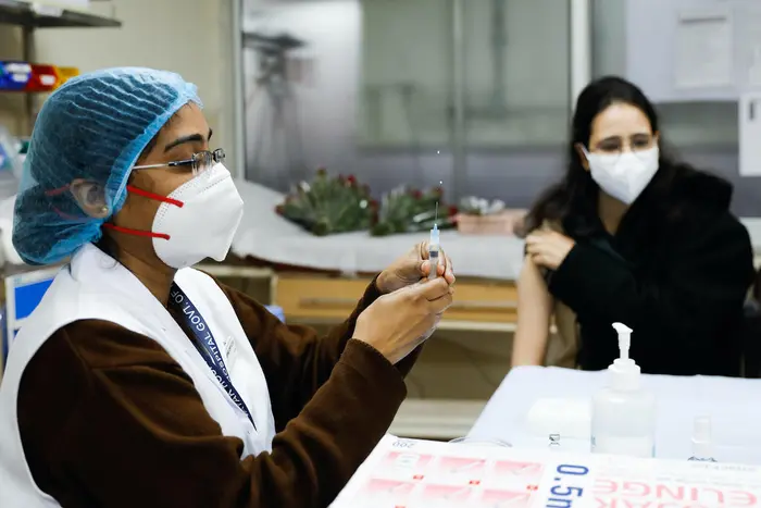 A vaccinator administers a COVID-19 vaccine to a health worker at Lok Nayak Hospital in New Delhi, India.