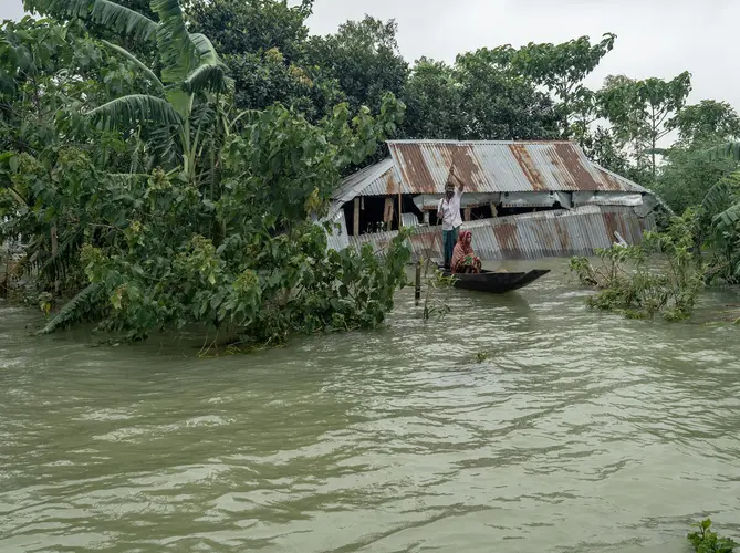 A family travels by boat after flash floods inundated northeastern Bangladesh in May and June 2022.