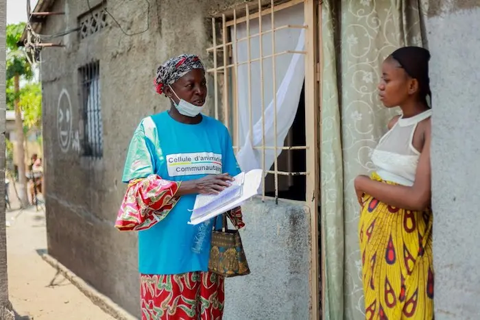 A member of a Community Action Cell speaks to a woman outside her home in Kinshasa to answer questions like "How safe is theCOVID-19 vaccine?" A member of a Community Action Cell speaks to a woman outside her home in Kinshasa to answer questions like "How safe is theCOVID-19 vaccine?"