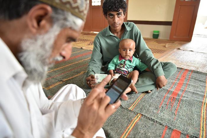 Father with his child at a mosque in Thatta district of Sindh province, Pakistan, where UNICEF and partners have launched a new digital birth registration service.