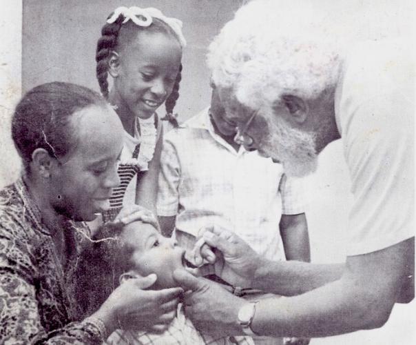 Gail Hoad, in braids, looks on while her brother receives the oral polio vaccine during a national immunization campaign in Jamaica in 1982.