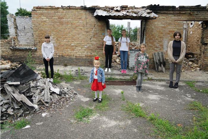 12-year-old Masha (left), little Lyuda, 11-year-old Lilya, 13-year-old Nelya, 10-year-old Anya and 16-year-old Yana stand among the ruins of a school in Horenka, Ukraine