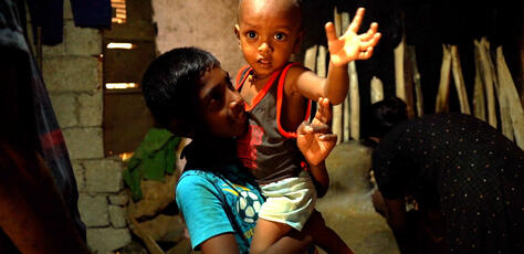 Ariesh, 10, holds his brother Aswin, almost 2, inside their home in rural Sri Lanka.