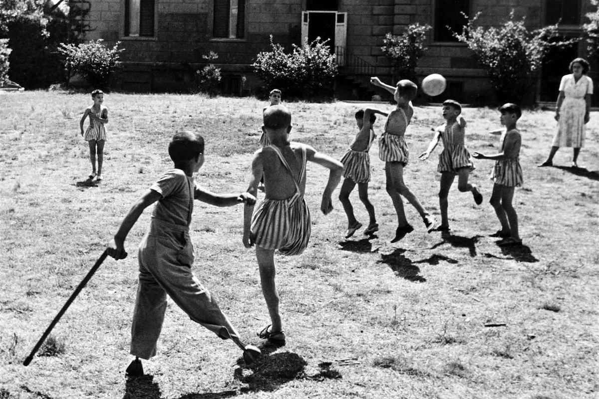 Children with disabilities play soccer on the lawn in front of an institution, circa 1950 in Italy.