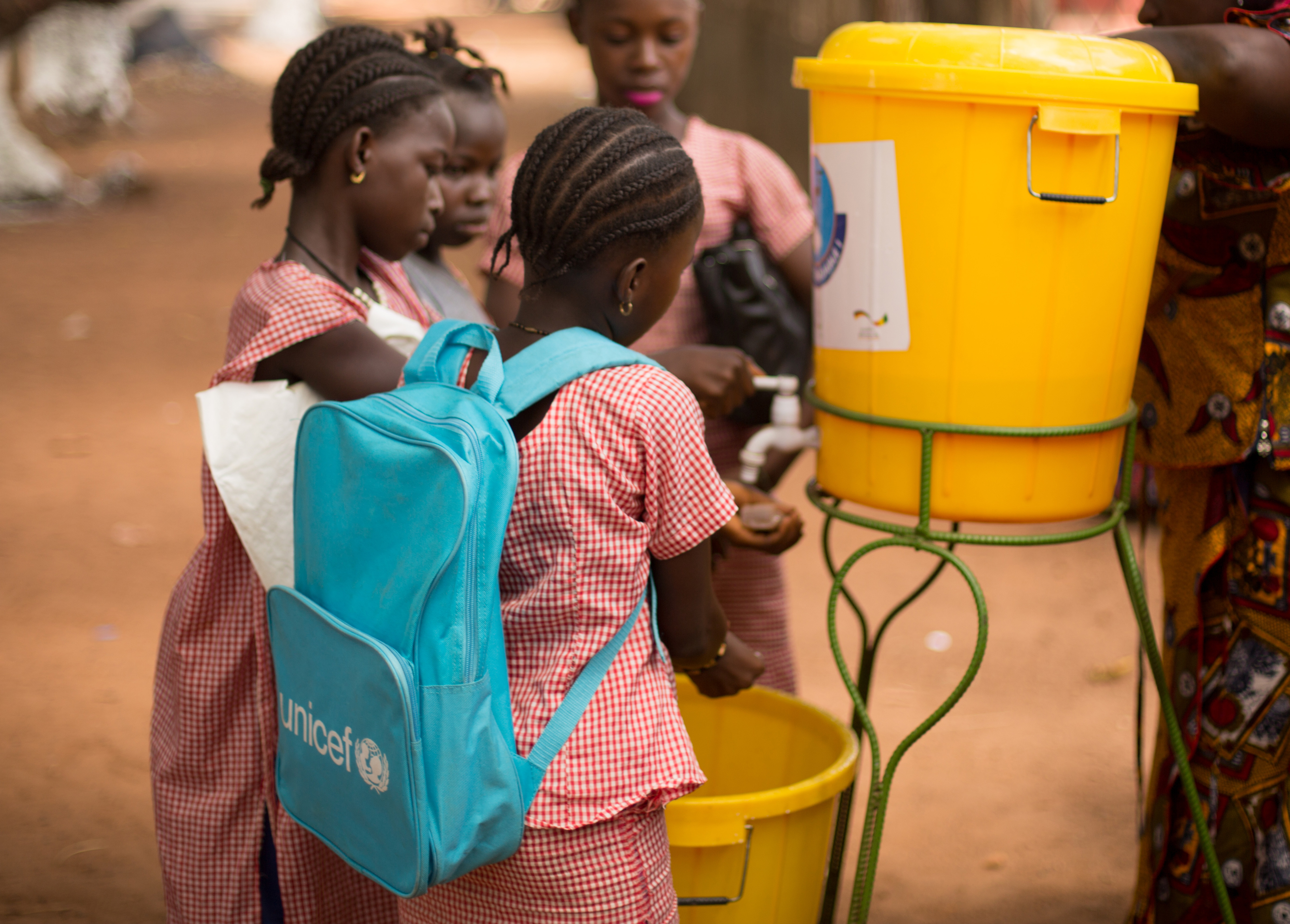 children in a UNICEF backpack getting water from a water cooler