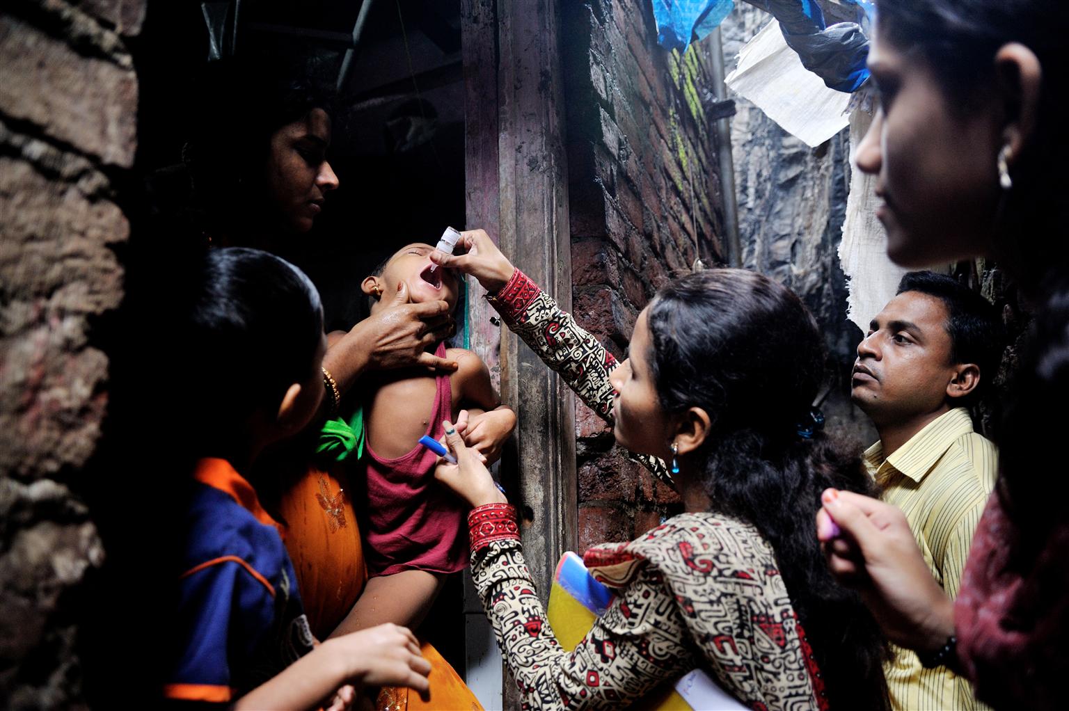 A boy is given a dose of oral polio immunization by a woman. 